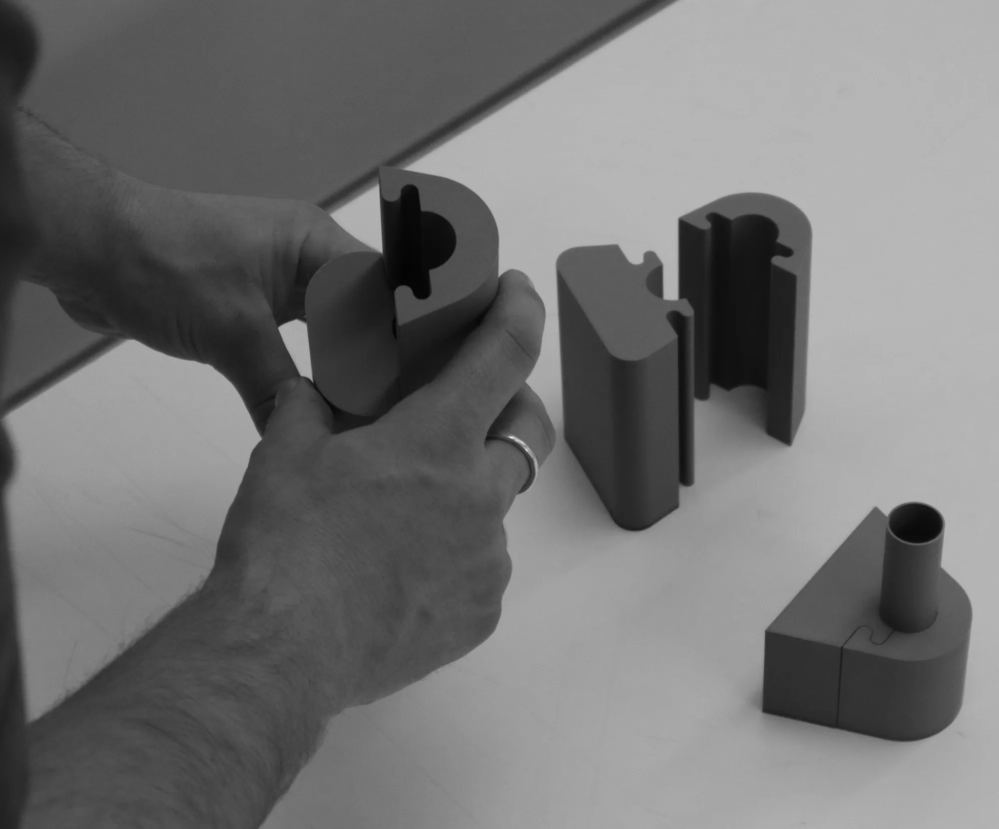 Hands holding matte silicone clamps that fit around a pipe.
